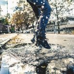 Person splashing in rain puddle; rainwater; rain harvesting; rainfall